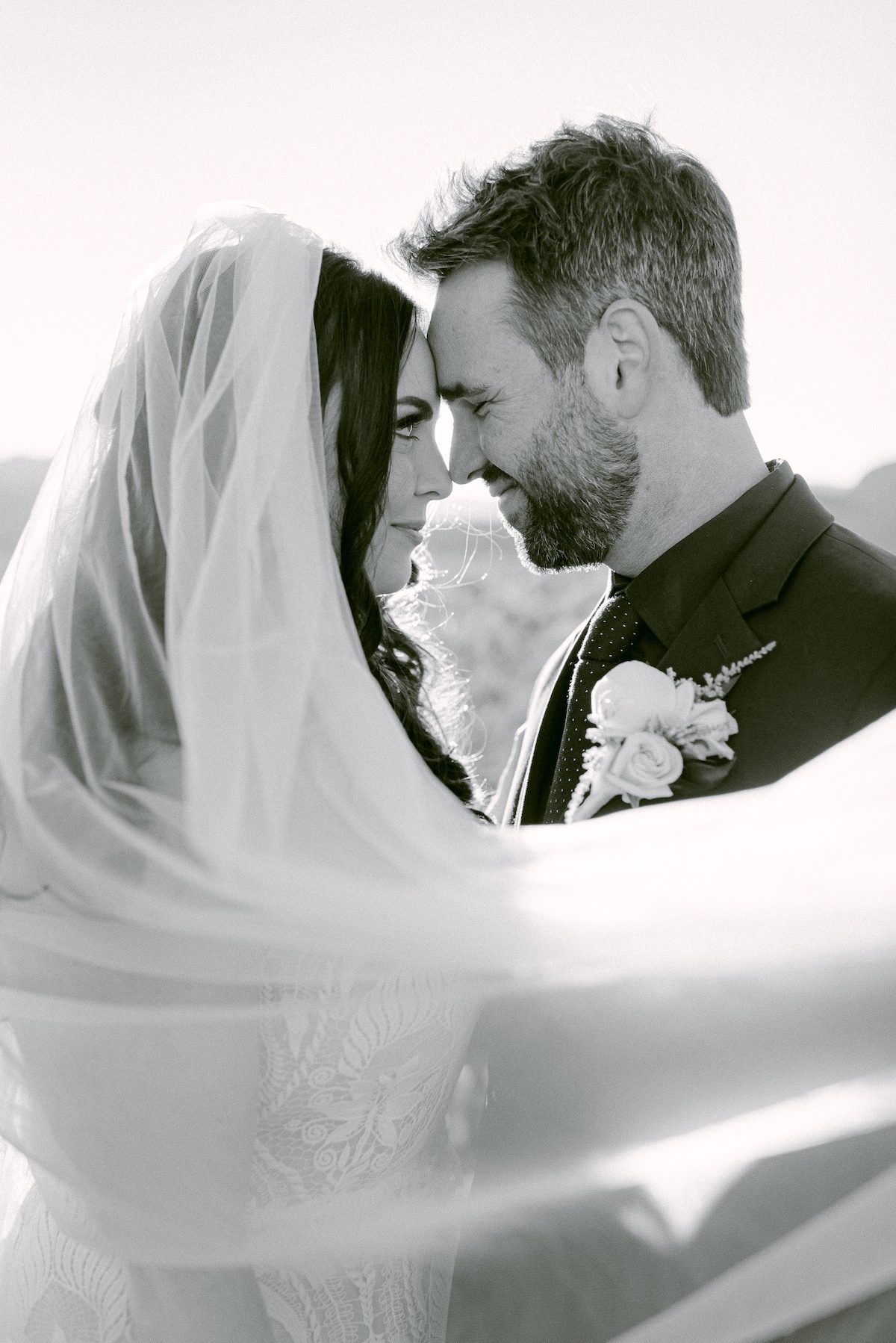 bride and groom draped in brides veil with foreheads in together in black and white Las Vegas Photographer Photography