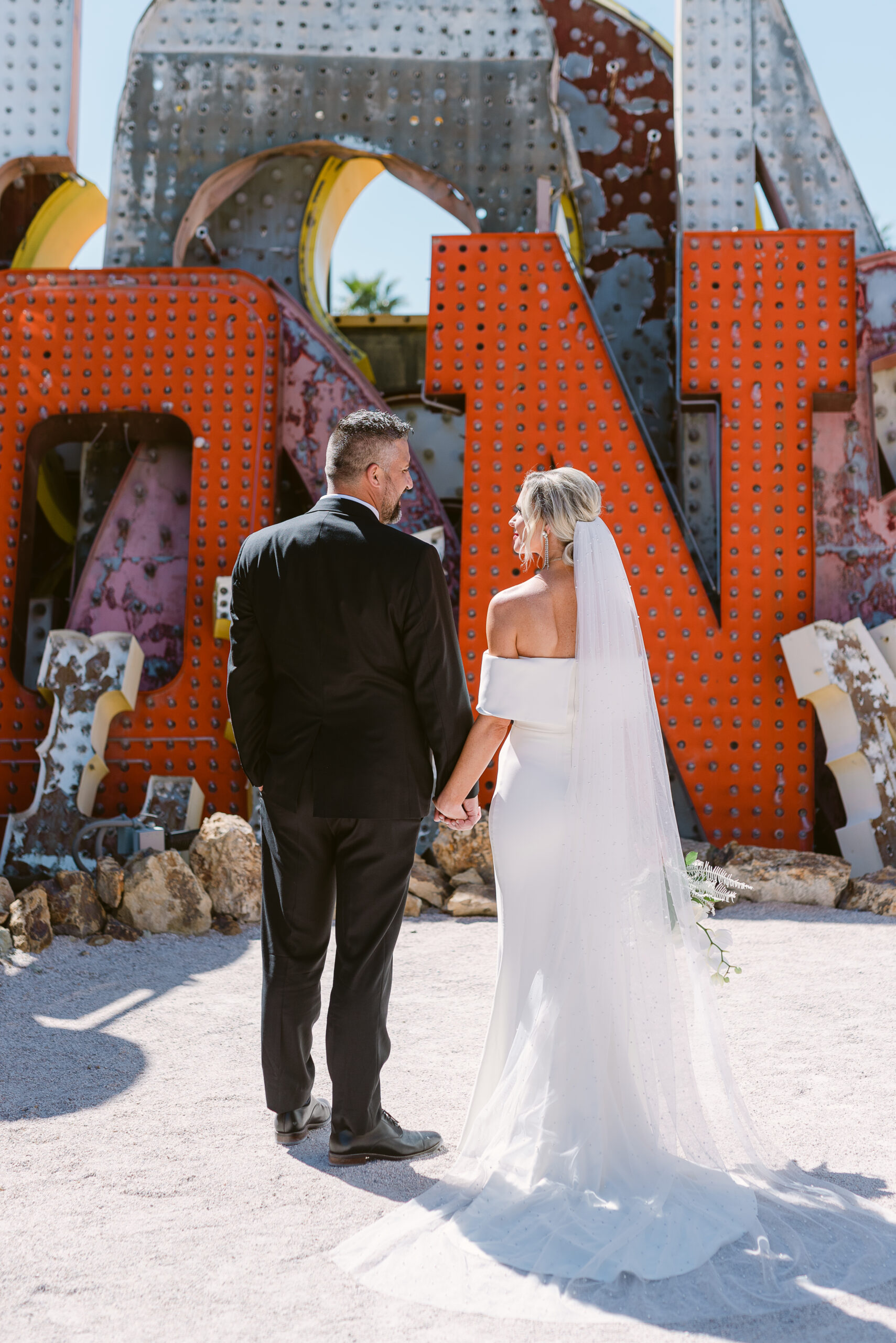 Wedding couple walking in Neon Museum in Las Vegas, NV with neon signs