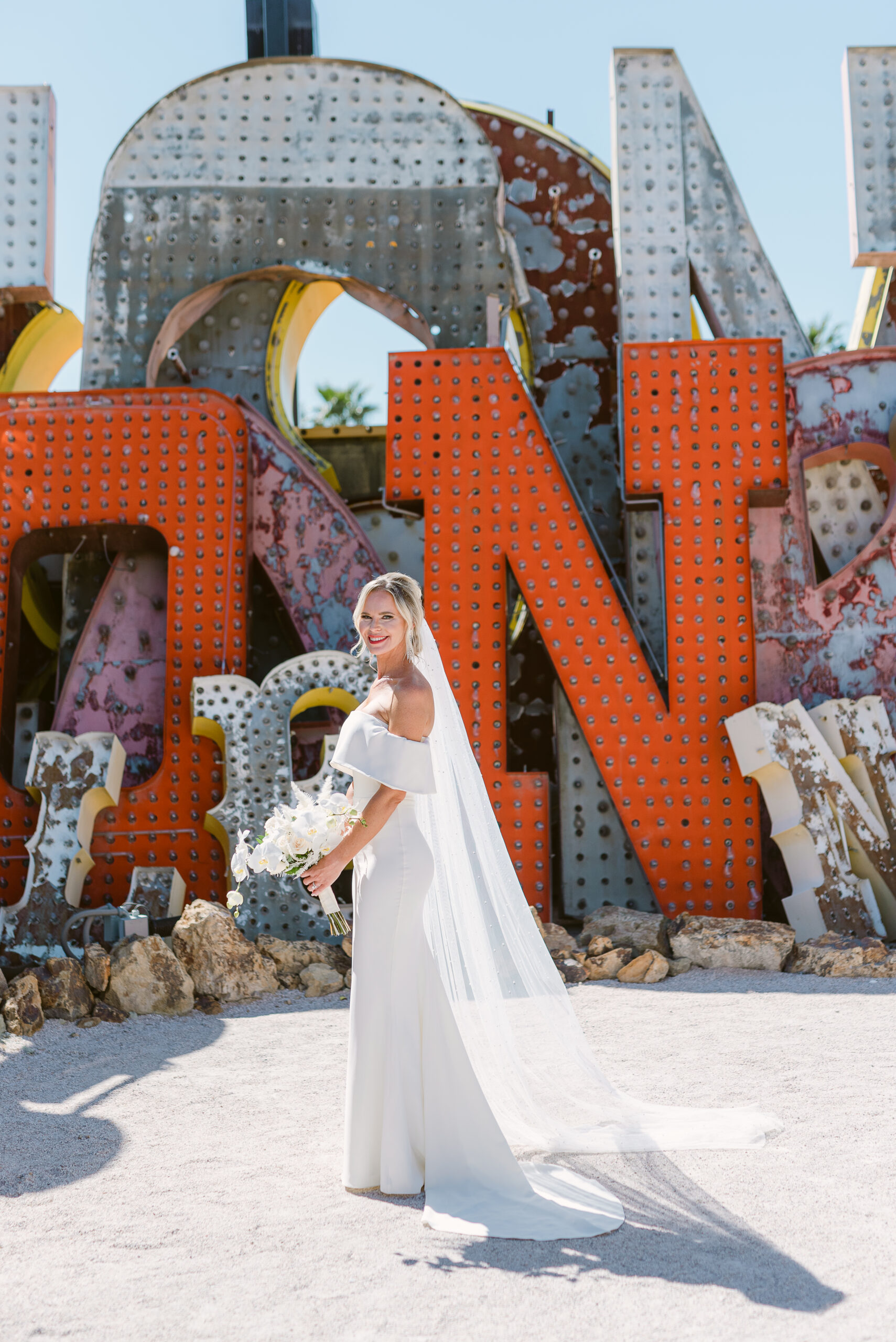 bride holding white orchid wedding bouquet in neon museum las vegas, nv