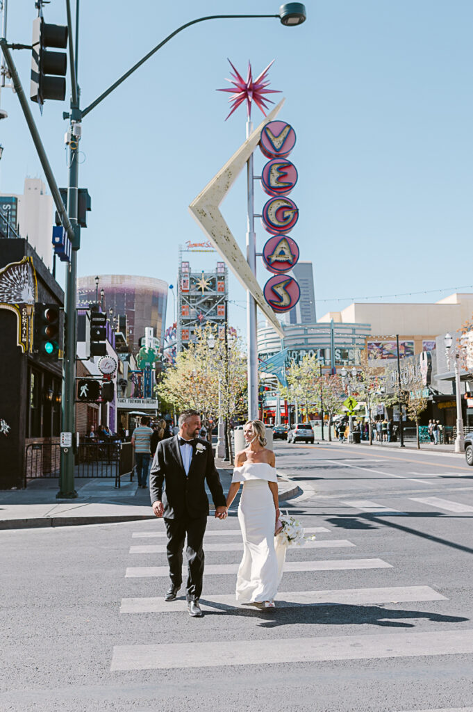 Wedding couple walking on Las Vegas Boulevard in downtown Las Vegas, NV with neon signs