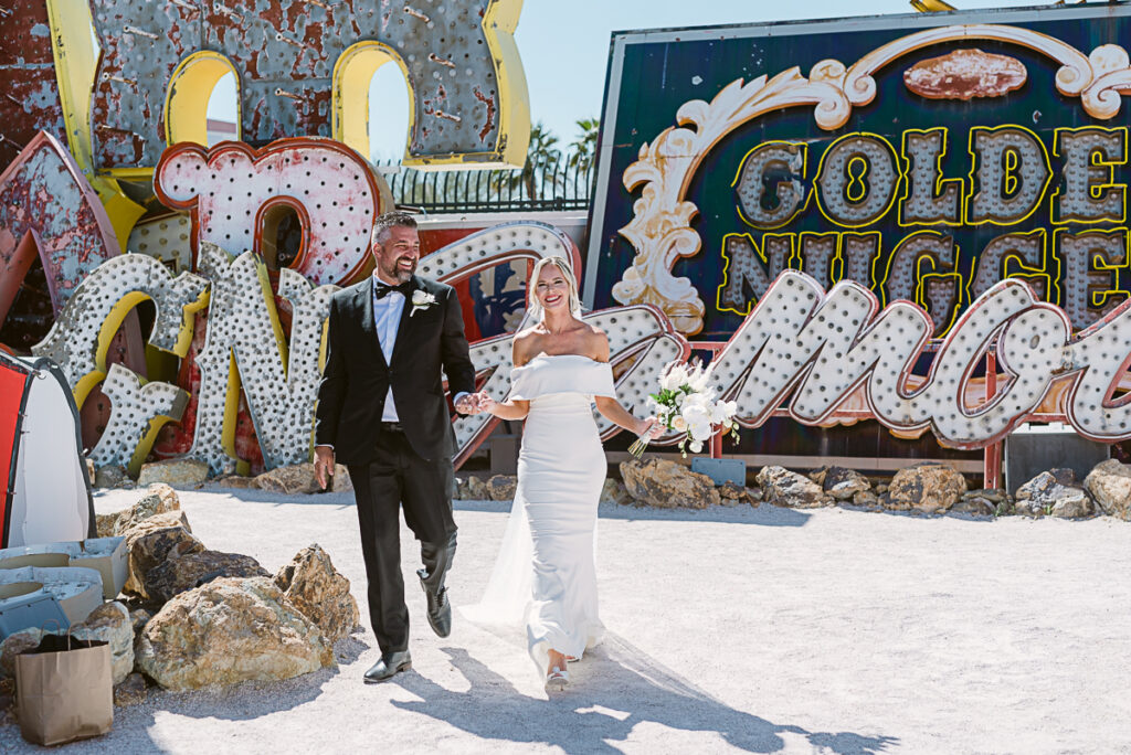 Wedding couple walking in Neon Museum Las Vegas, NV with neon signs Couple sharing first kiss at wedding in Neon Museum Las Vegas