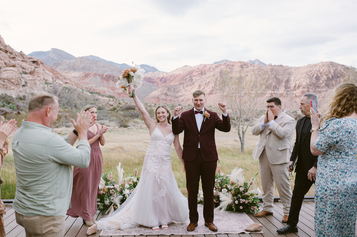 wedding couple celebrating holding rustic bouquet at elopement in red rock canyon