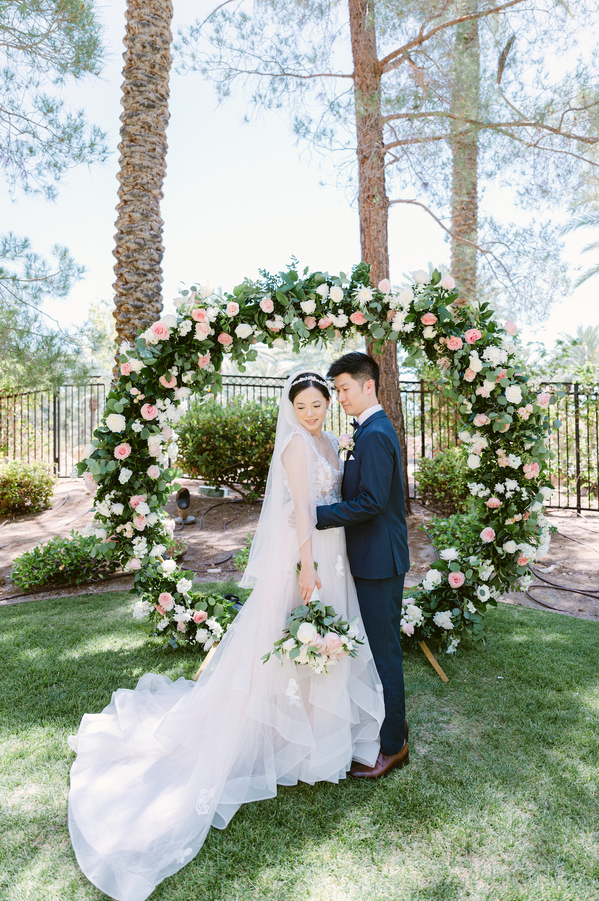 wedding couple embracing with floral arch backdrop at JW Marriott Las Vegas